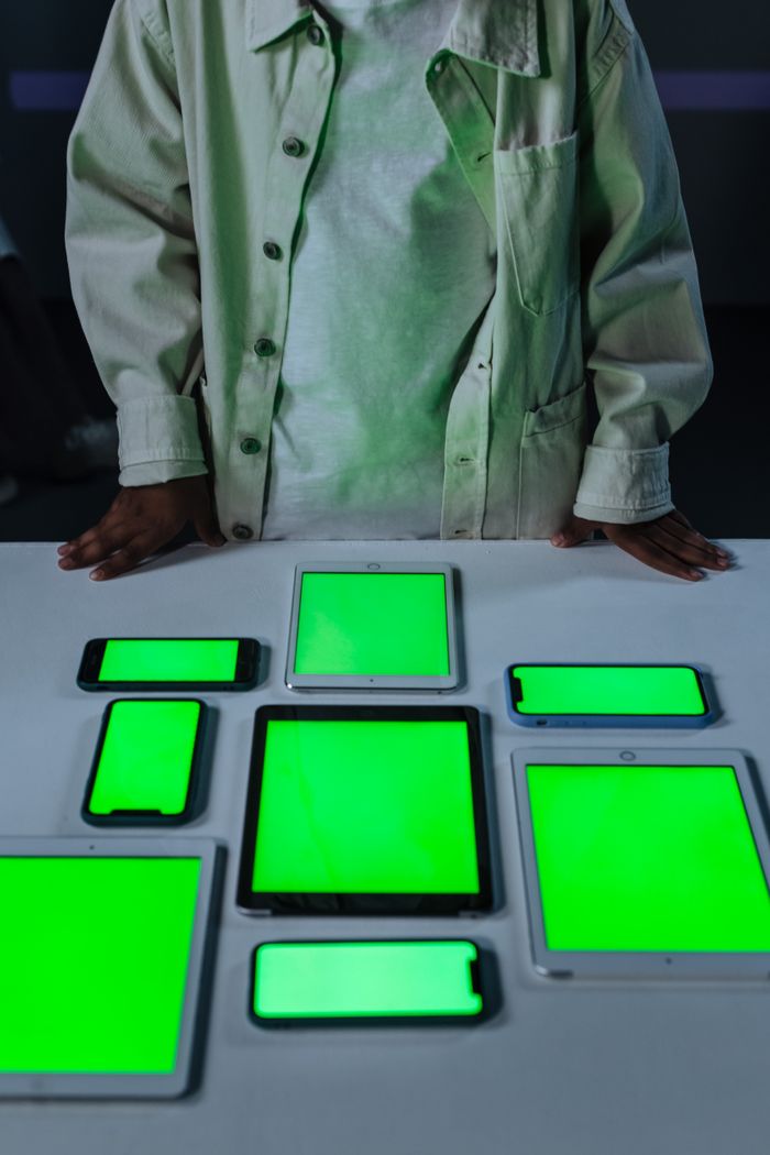 About Nine digital devices on a table with green screens, ready for content editing.