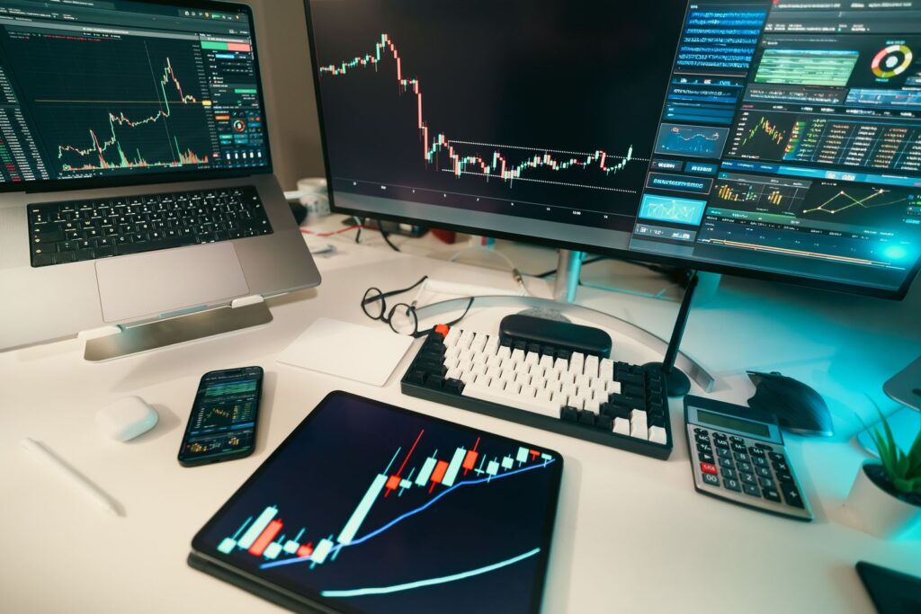 Schermi di una postazione di trading con grafici finanziari e dati di mercato